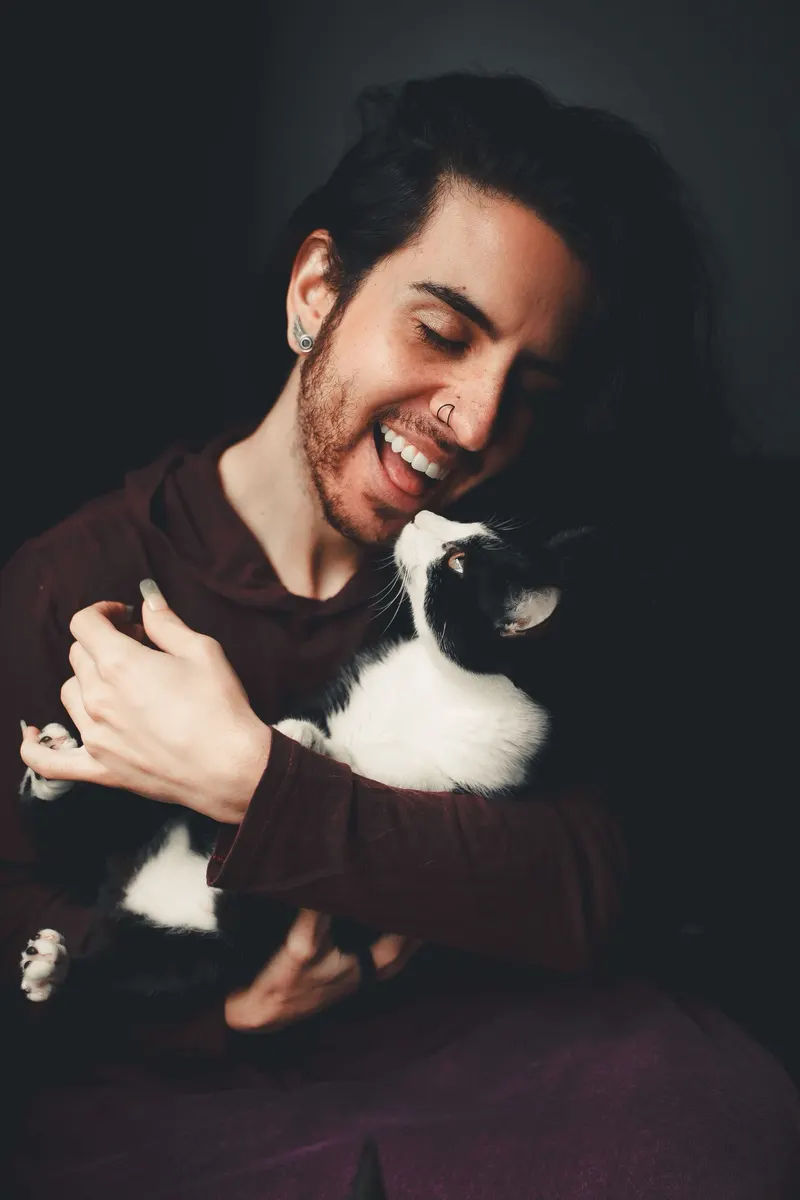 Un homme souriant serre son chat noir et blanc